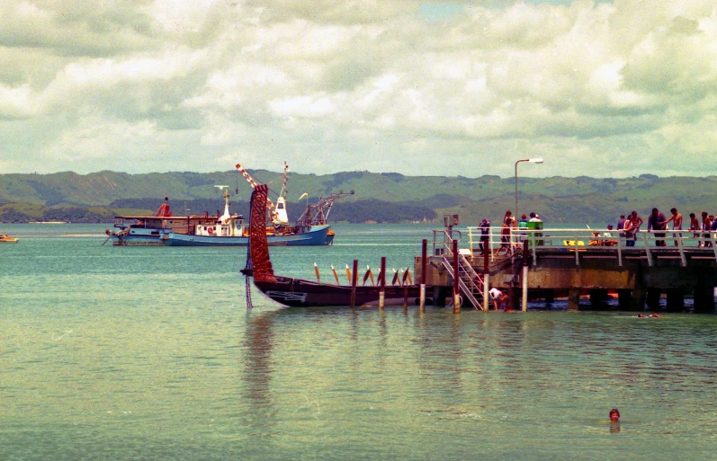 a harbor with a boat docked, and several people near the dock