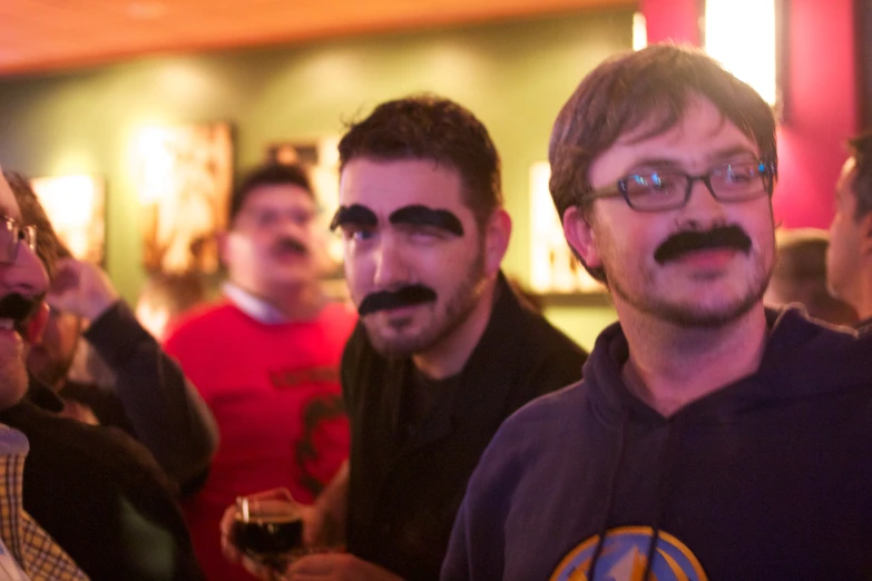 three men with fake moustaches standing in front of a crowd