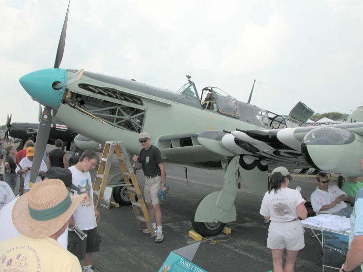 people standing around a military plane on a runway