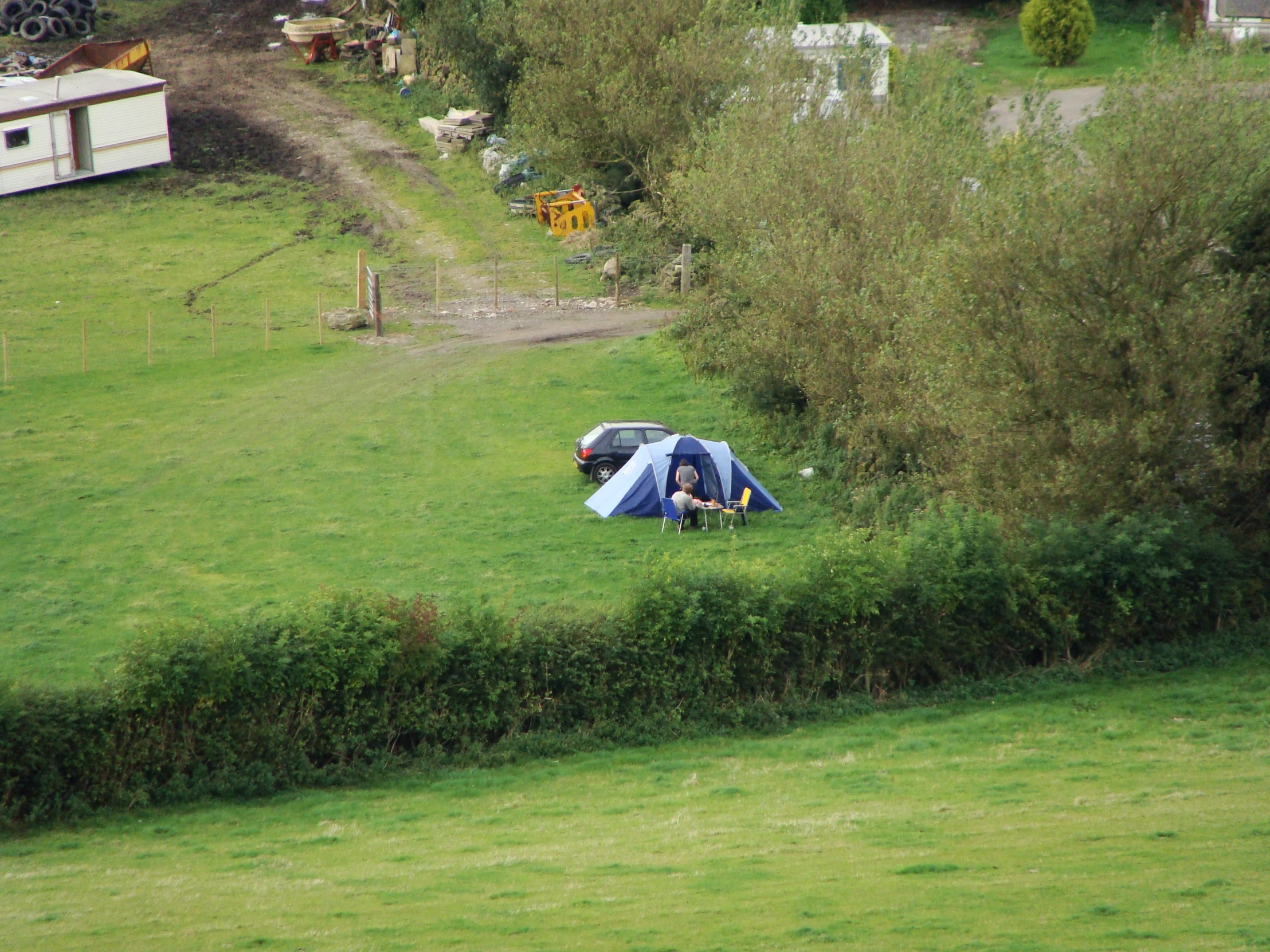 a tent pitched on top of a green hill