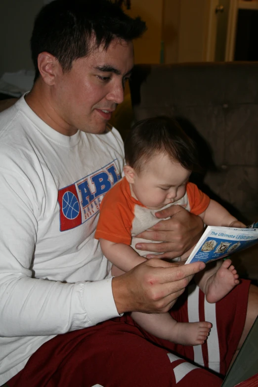 a man reading a magazine to a young child
