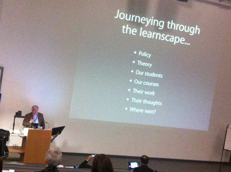 a speaker is shown talking in front of an audience