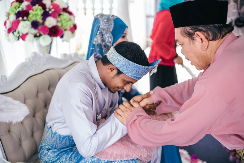 two people at a wedding putting on their traditional clothes