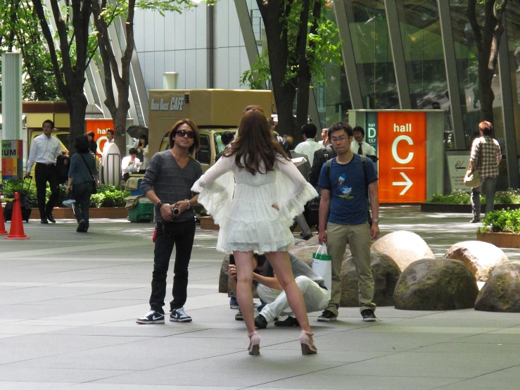 a woman dressed in white walks past people