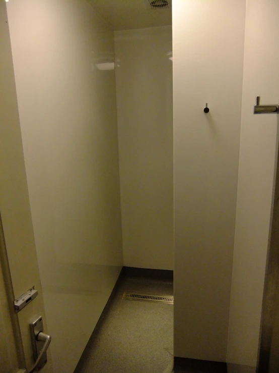 a long empty bathroom area with toilet paper hanging on the wall
