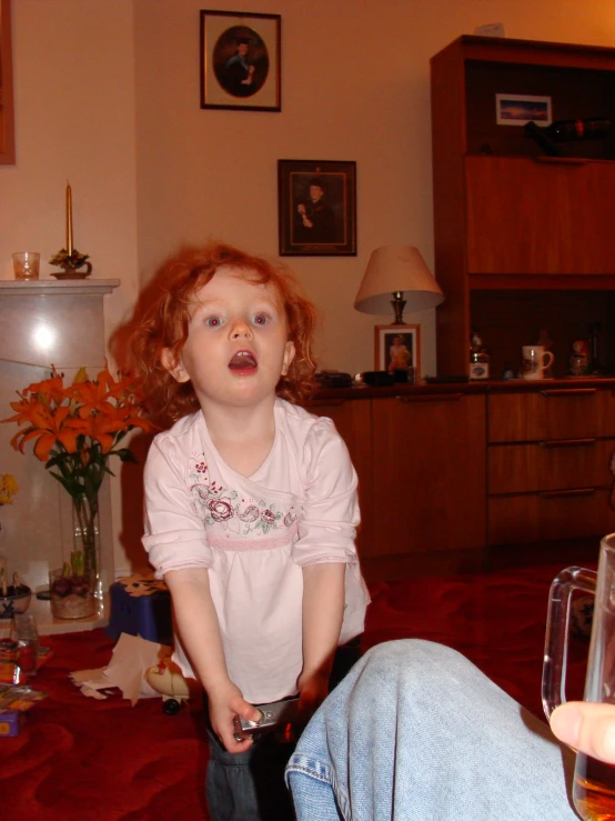 a child standing on the floor with a wine glass in front of her