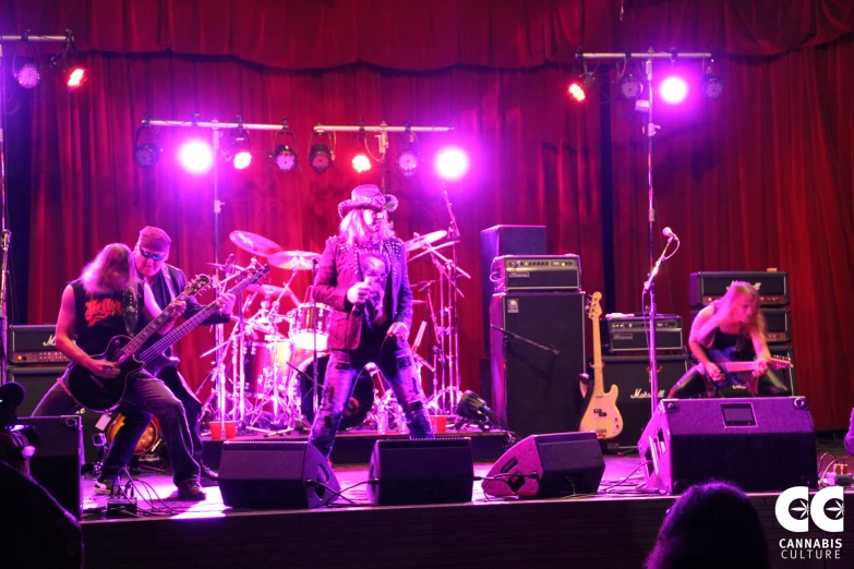 three people are playing instruments in front of purple lights