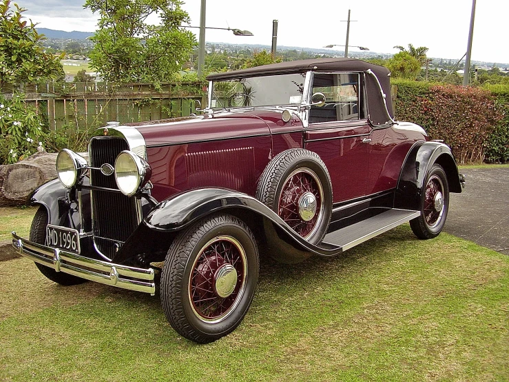 a red antique car parked in the grass