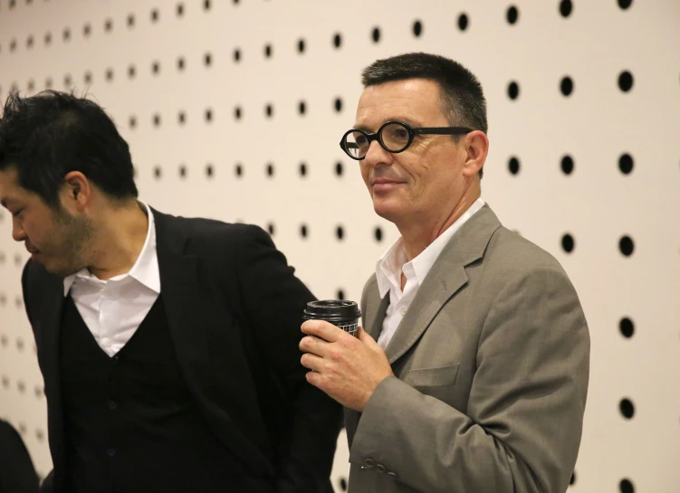 a man with glasses holding a camera and another man wearing a suit