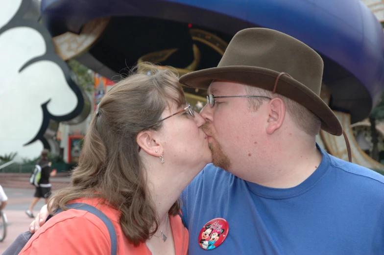 a man and woman sharing a kiss in front of a carousel