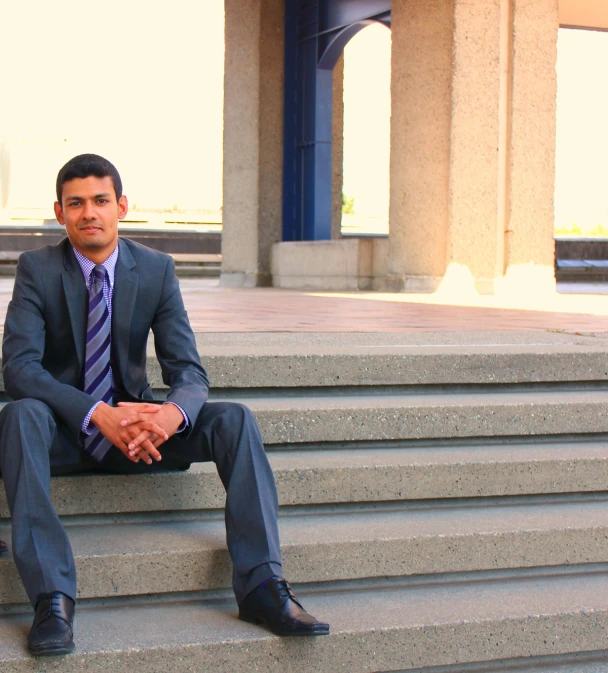 a man wearing a suit and tie sitting on steps