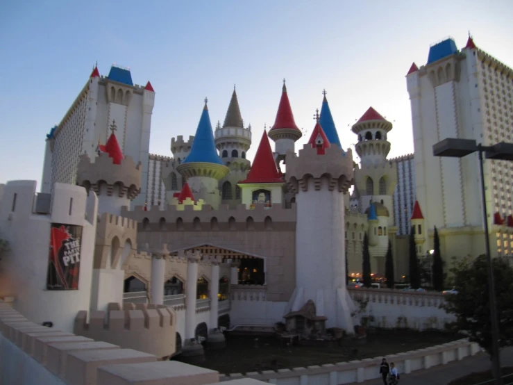 a large castle with red, white, and blue turrets is in front of other buildings