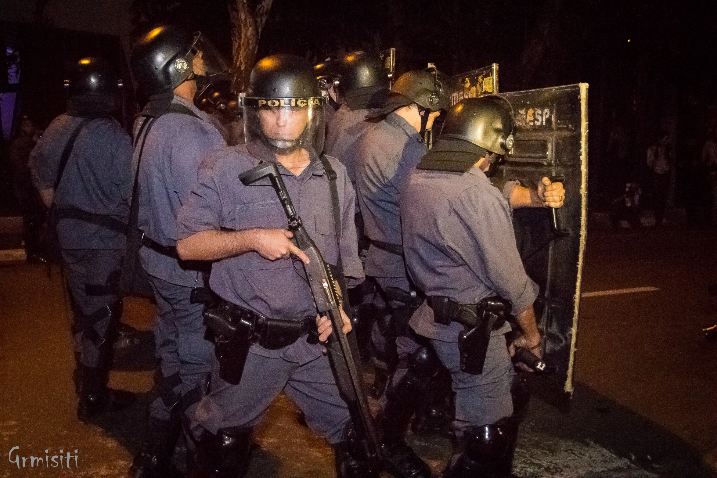 police standing behind shields as they stand in the street