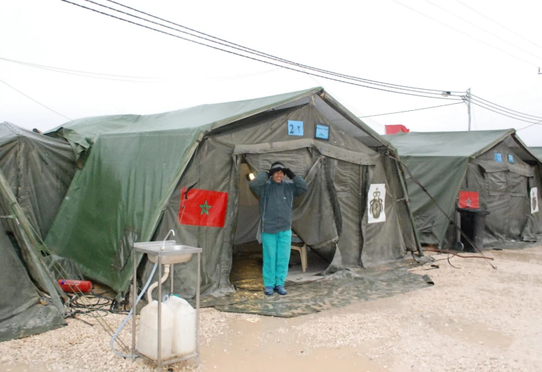 a man standing in the door of a building next to a lot of tents