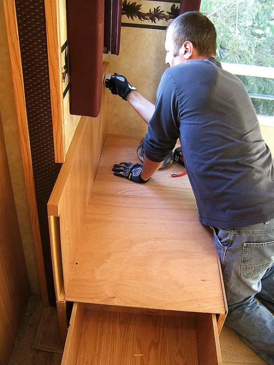 a young man sanding on an old wooden dresser