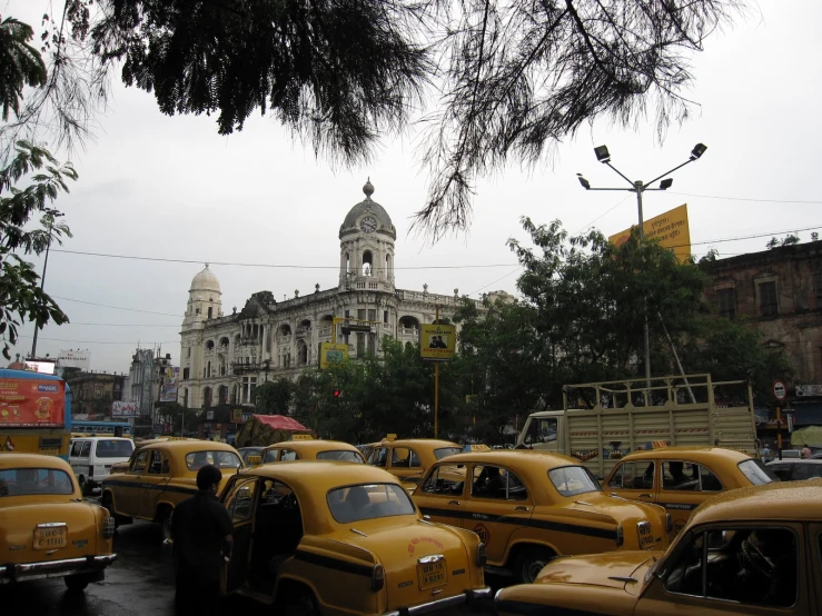 a parking lot full of old model yellow taxis in a foreign city