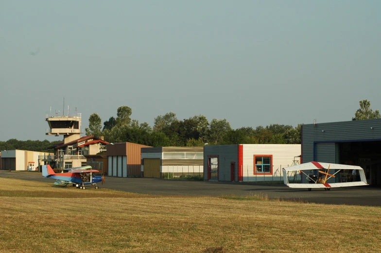 three small planes are parked in front of a small hangar