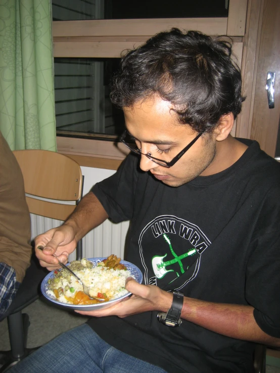 a man is eating out of his plate while looking at the food