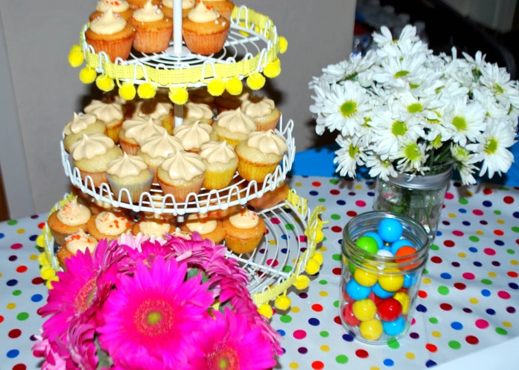 a cake stand with cupcakes and flowers on a table