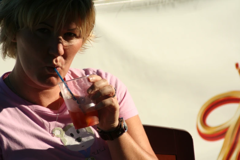 a woman with a straw in her mouth holding a drink