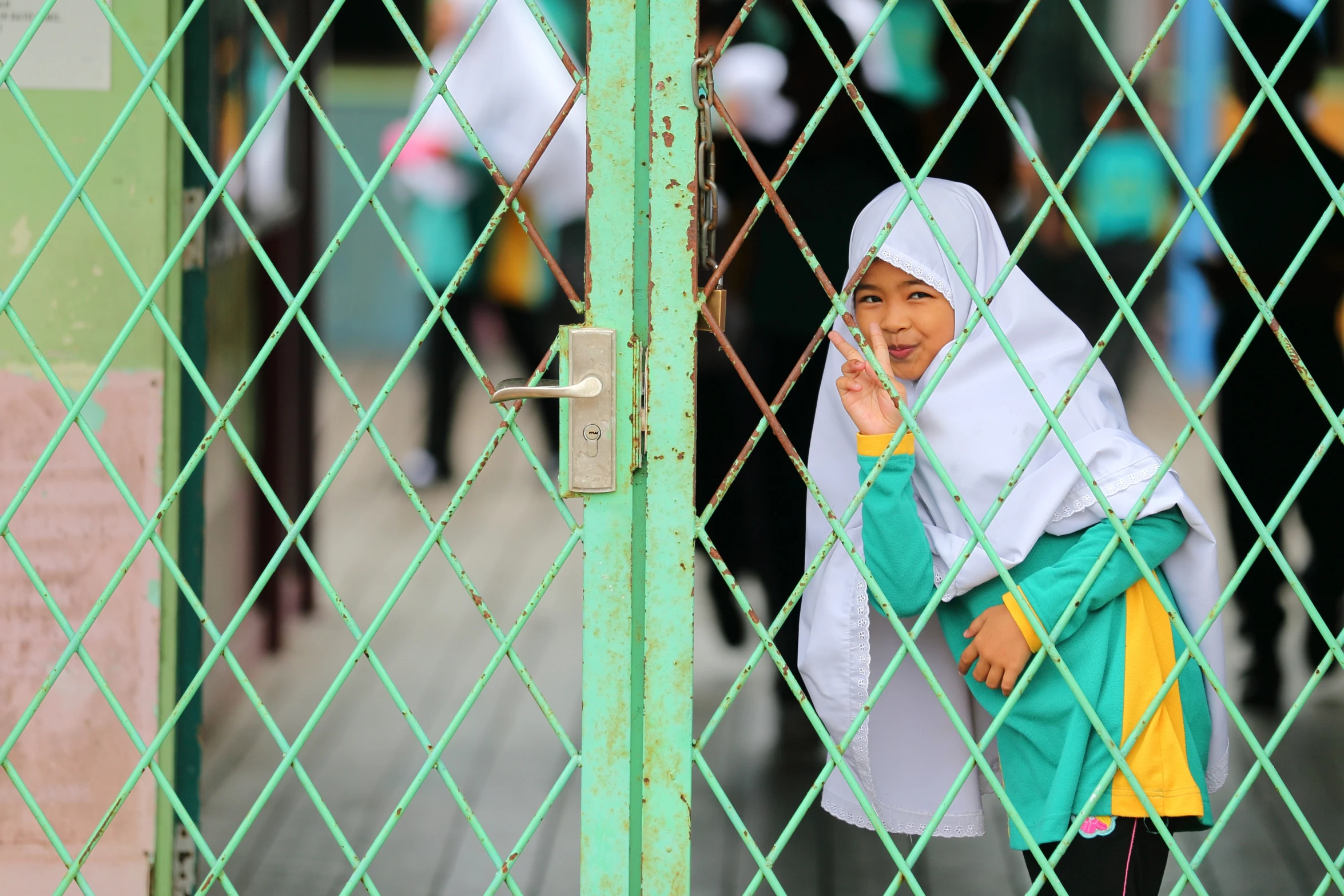 a woman looking through a gate with a yellow hat