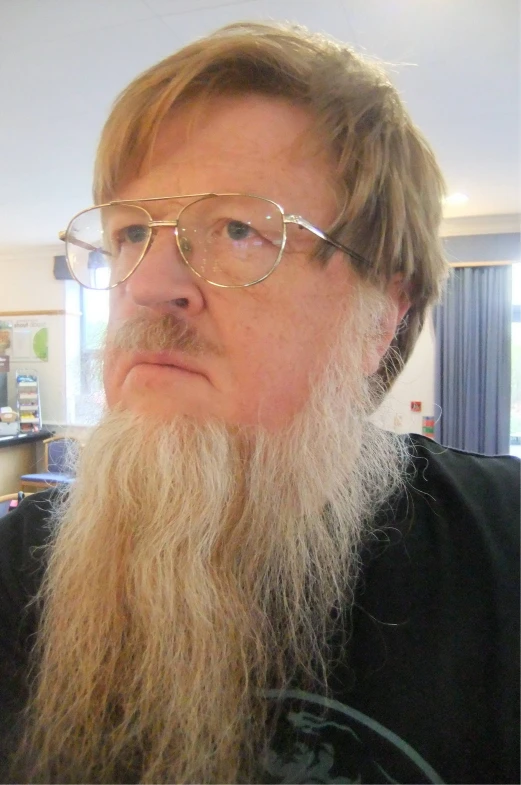 a man in glasses and a beard looks away from the camera