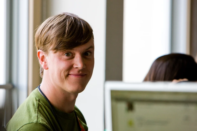 a man with blonde hair wearing a green shirt and looking at the camera