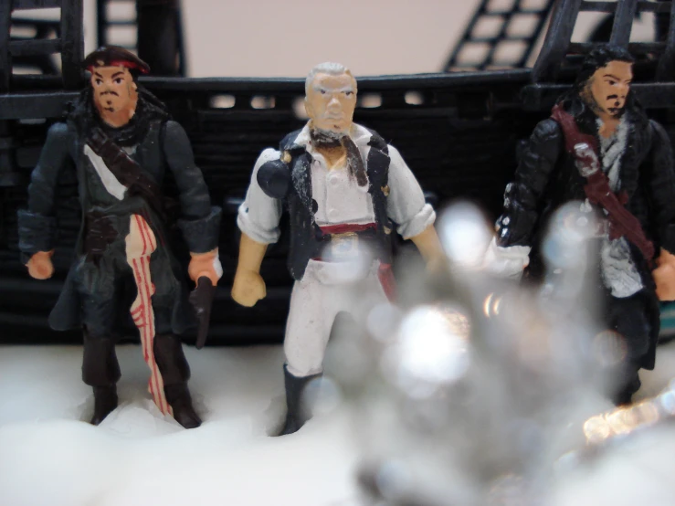 three action figures of pirates are posed on top of a table