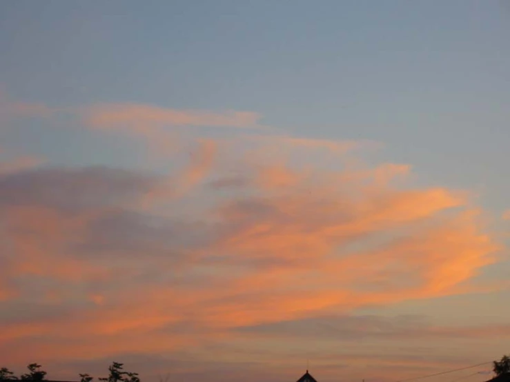 a pink sky with clouds on the horizon and some buildings