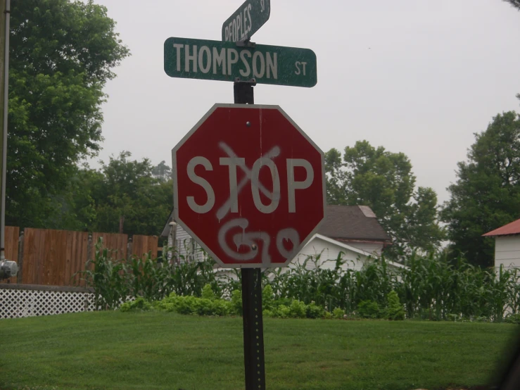 the stop sign with a spray painted word is seen at an intersection