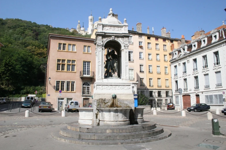 statue with arches in front of buildings next to a square