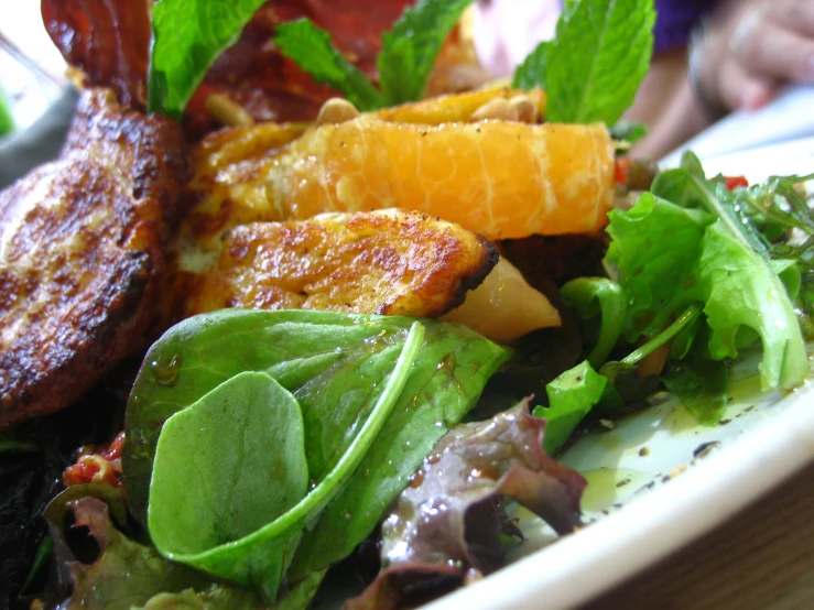 a plate of salad topped with meat and oranges