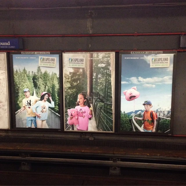 a train station with posters on the wall above it