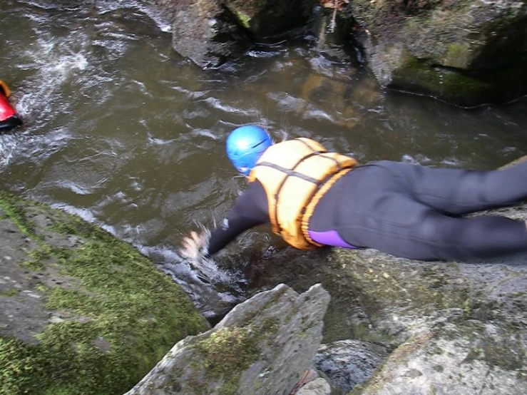 a man diving in the river near some rocks