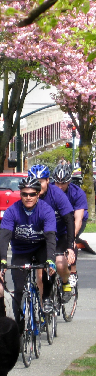 a group of people riding bikes down a street next to a forest