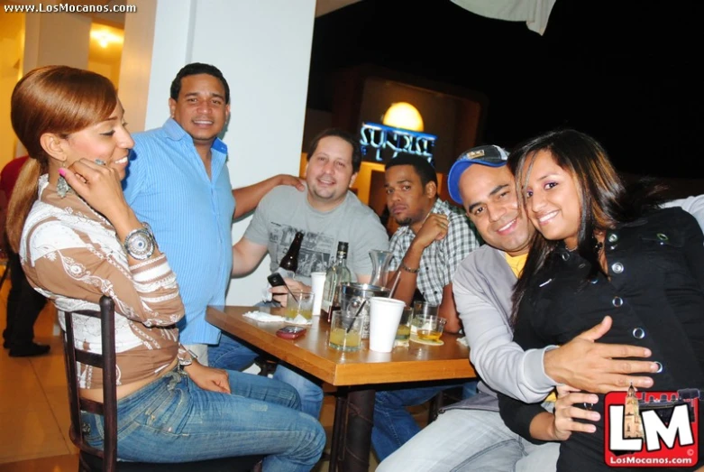 group of people sitting around a small restaurant dining table