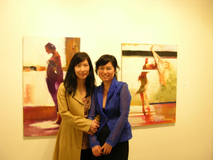 two young women posing for a po in front of some art