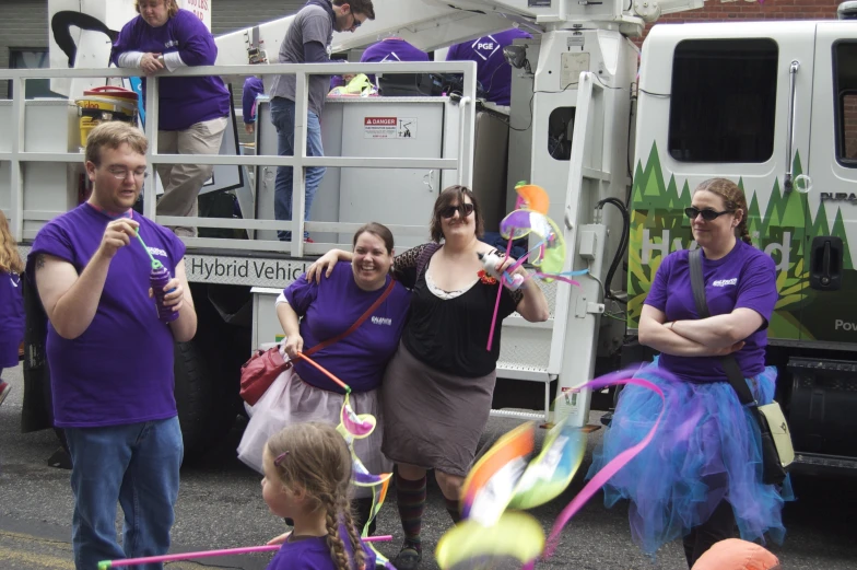 women stand in front of a large truck while holding onto kites