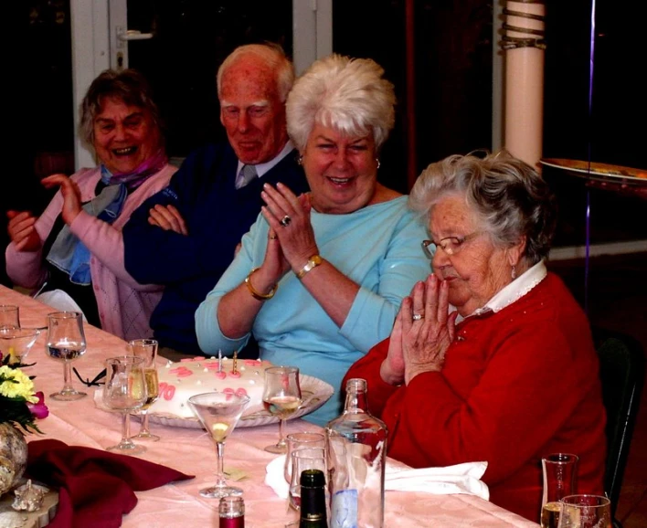 a group of older women clapping around the table
