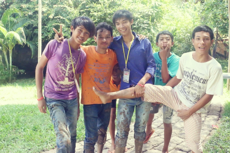 children are posing for the camera with their foot in mud