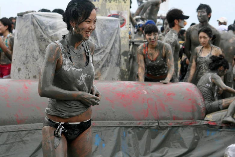 a woman covered in mud with other people in the background