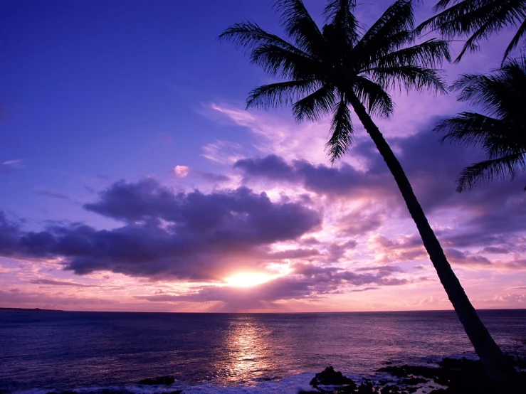 the sun peeking through clouds at sunset by the water