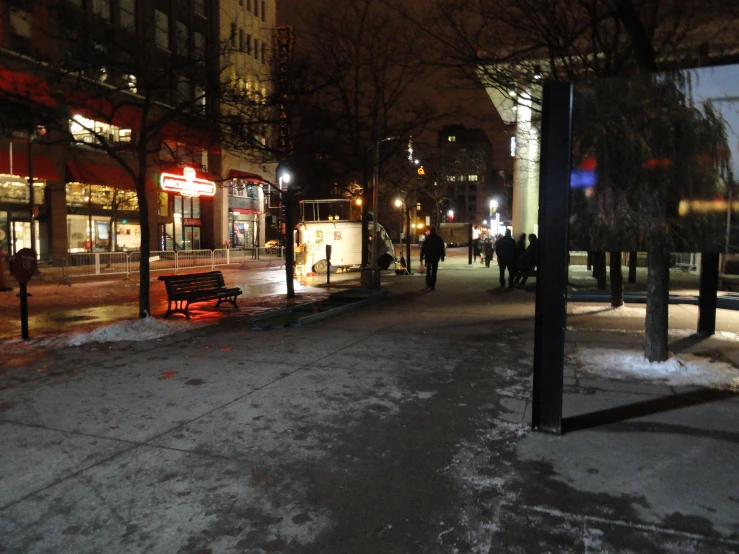 a group of people walking down a street at night