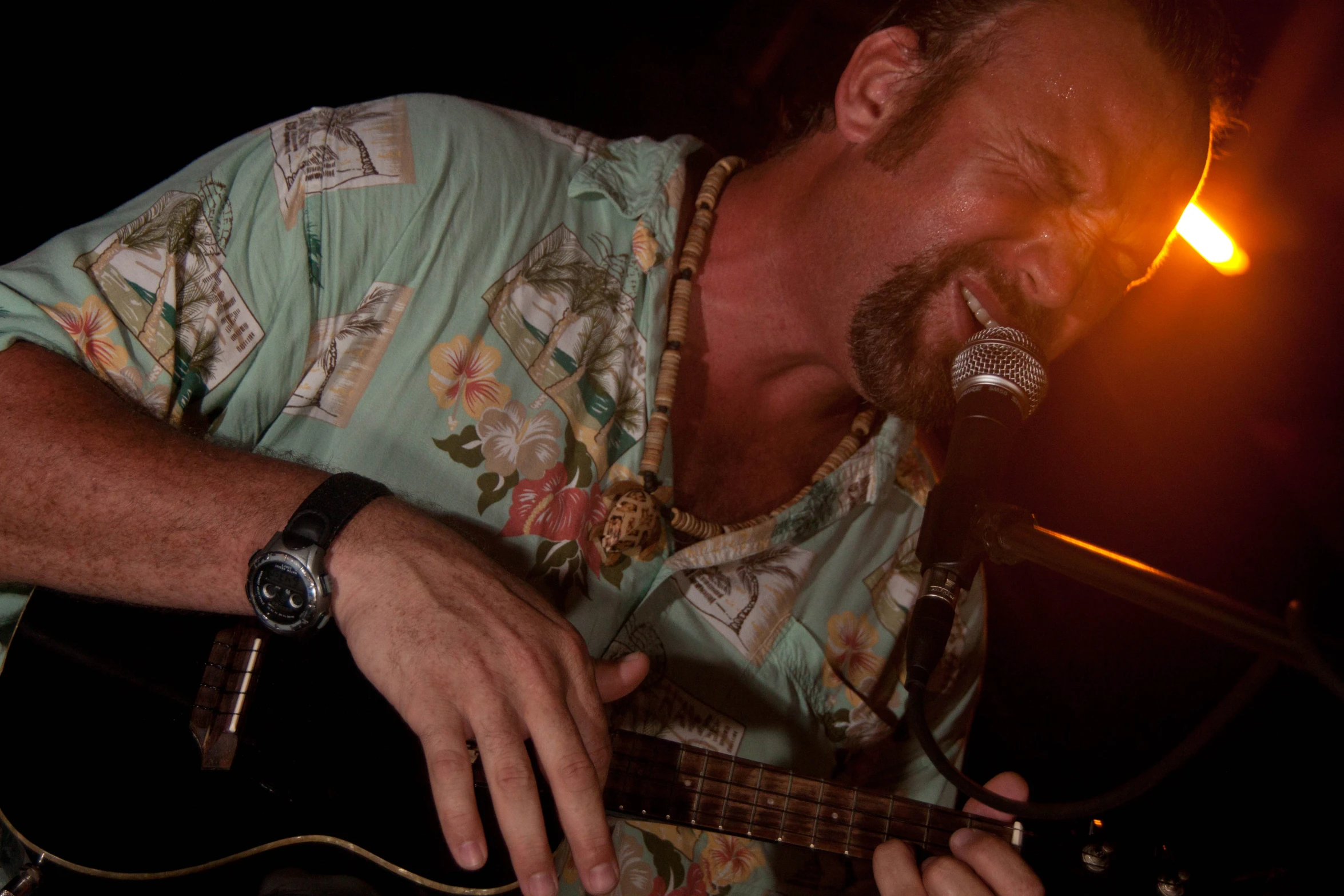 a man plays his guitar while drinking a glass