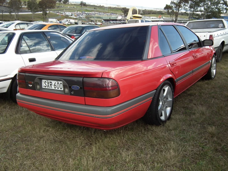 a red car is parked in a lot full of other cars