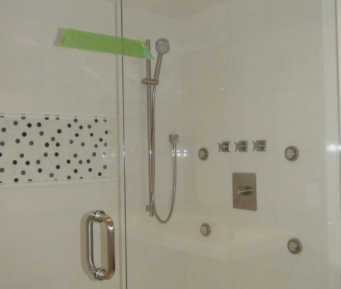 the wall and shower with a green towel in it