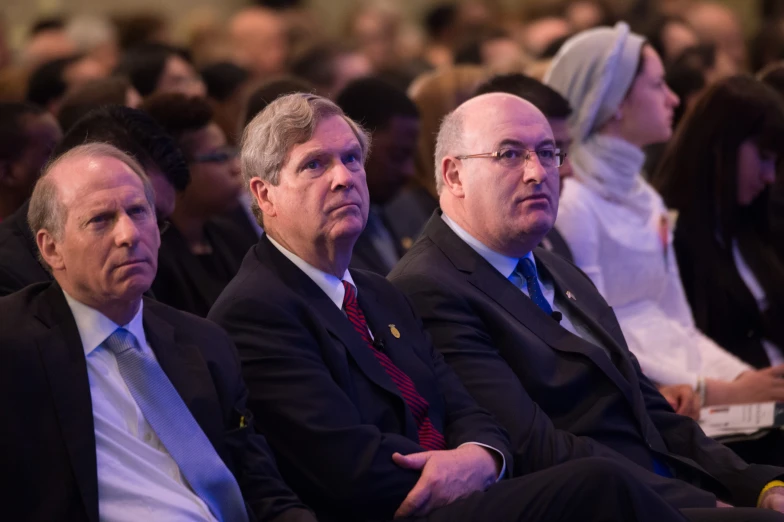 three men sitting in a row with microphone in their hand