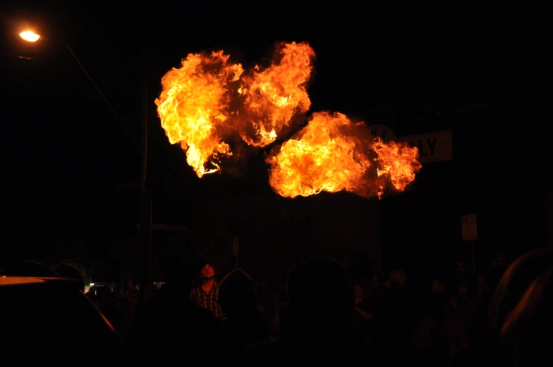 a large fireball at night surrounded by a group of people