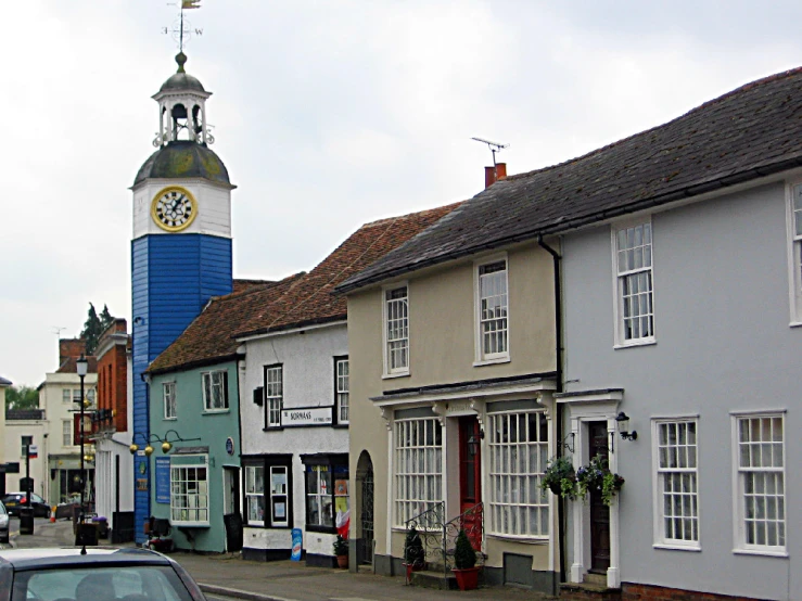 a town with cars parked and an clock tower in the distance