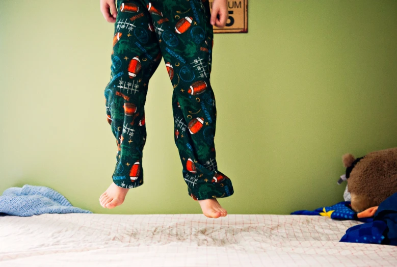 a person with some pajamas on jumping on a bed